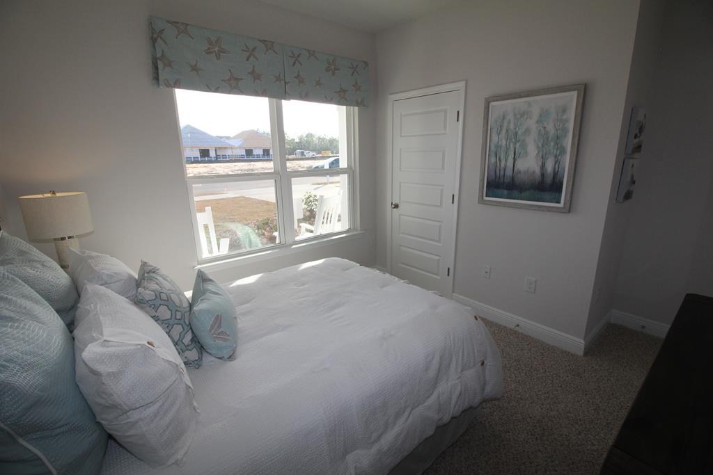 Bedroom with a white bed, pale blue pillows, and a starfish-patterned window valance.