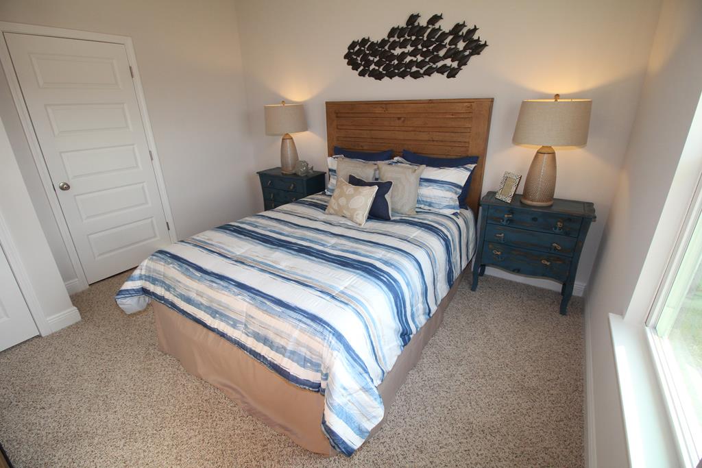 Furnished bedroom with blue-and-white striped bedding, wooden headboard, and matching blue nightstands.