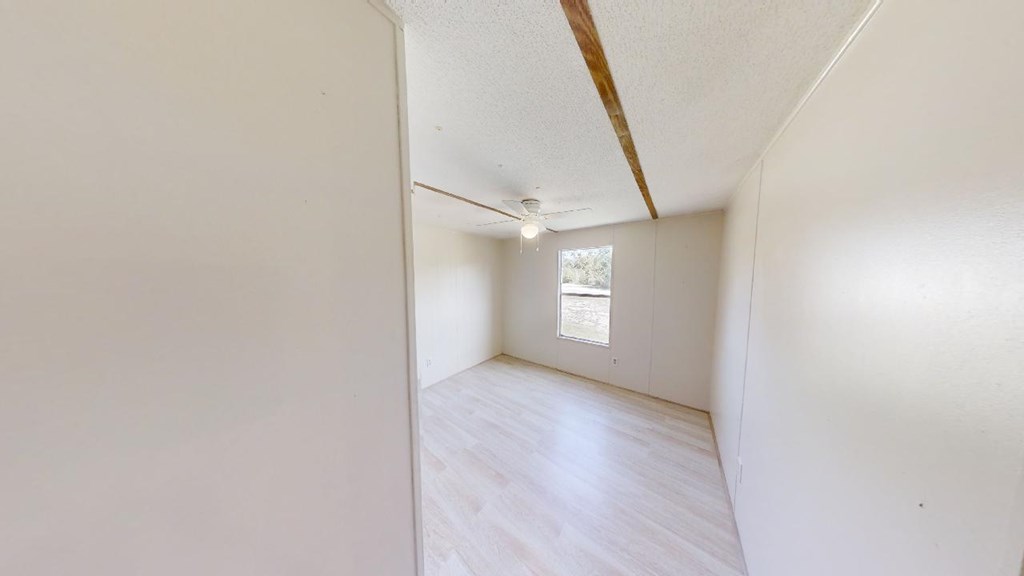 Empty room with pale flooring, a ceiling fan, and a window.