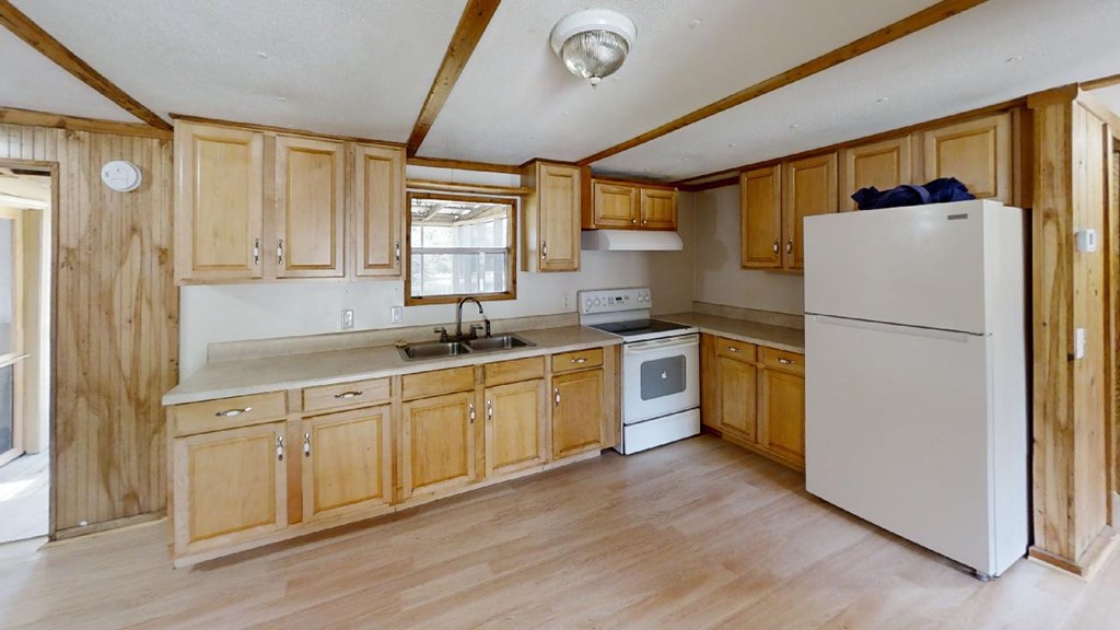 Kitchen with light wood cabinets, a double-basin sink, and white appliances.