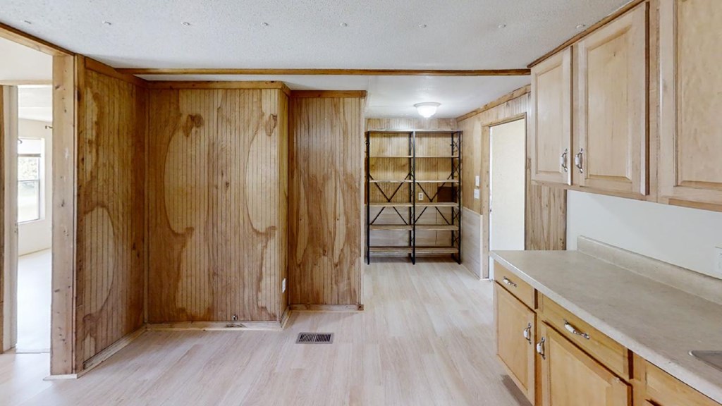 Wood-paneled room with built-in cabinets, a long countertop, and open shelving.