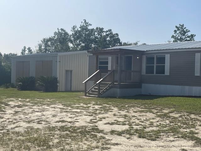 Single-story gray home with a raised porch, wooden steps, and attached metal-sided addition.