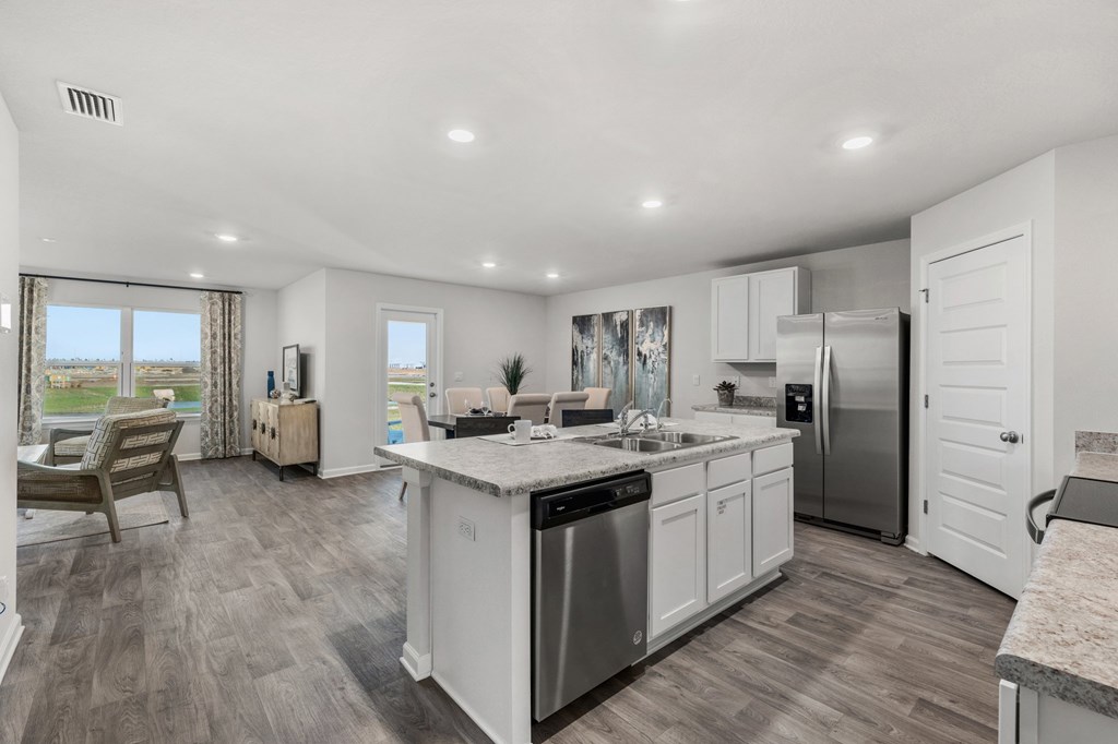 Open-plan kitchen with a large stone island, white cabinetry, and stainless steel appliances.