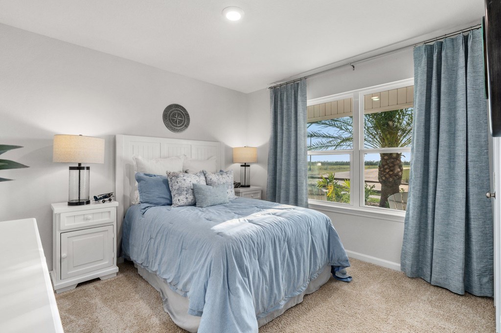 Bedroom with pale blue bedding and curtains, looking out to a palm tree.