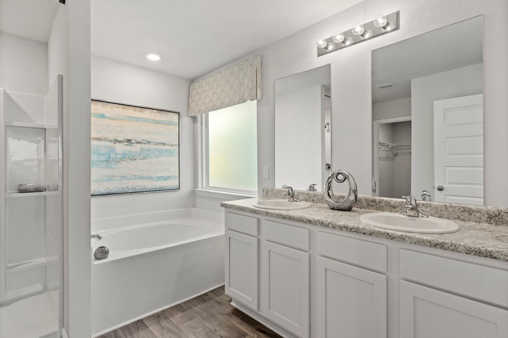 Bathroom with a bathtub beside a double-sink vanity and large mirrors.
