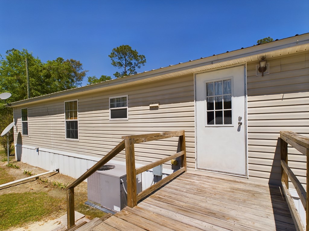 Home exterior with a white entry door and weathered wooden deck and ramp.