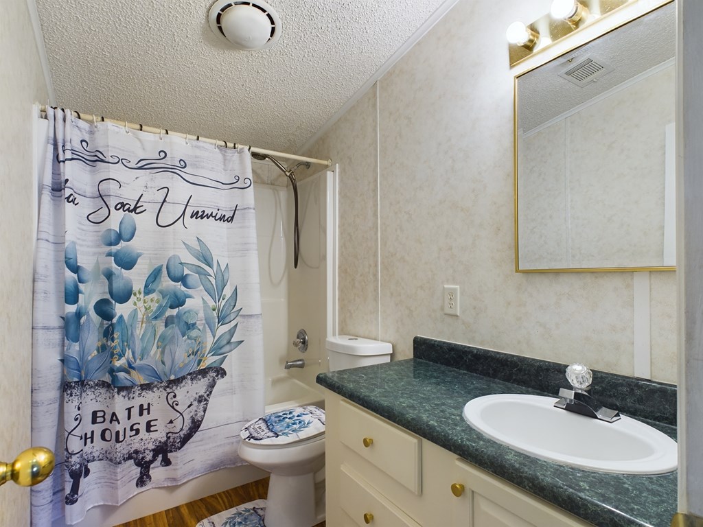 Bathroom with a blue floral shower curtain and white vanity topped with dark green counter