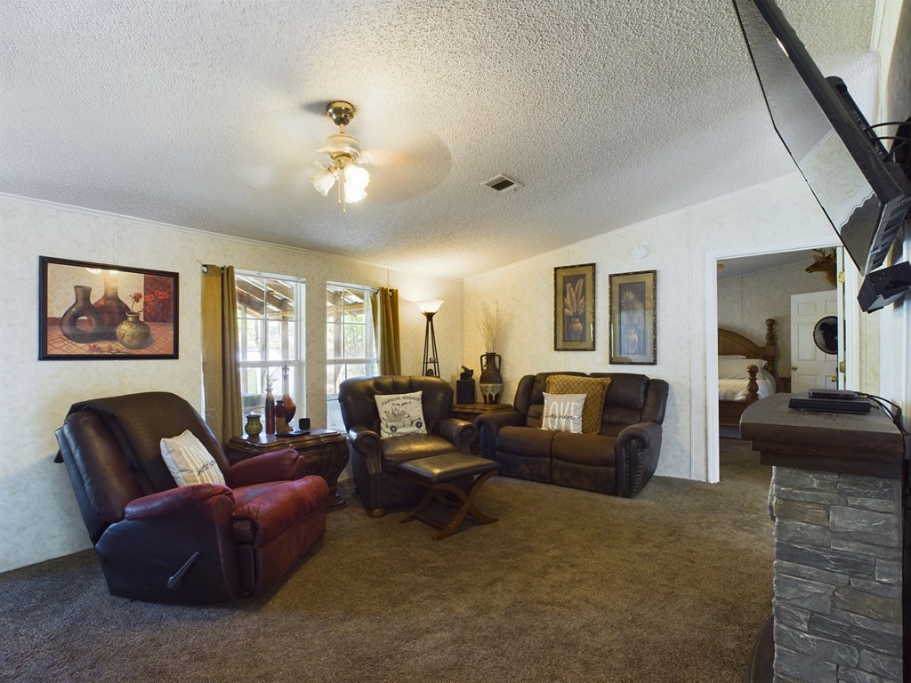Living room with brown leather seating, two windows, and a doorway to a bedroom.