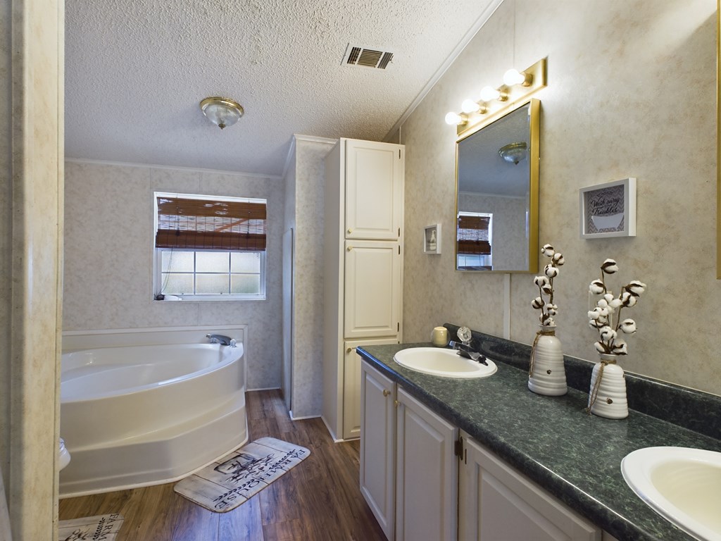 Bathroom with a corner soaking tub and a long double-sink vanity.