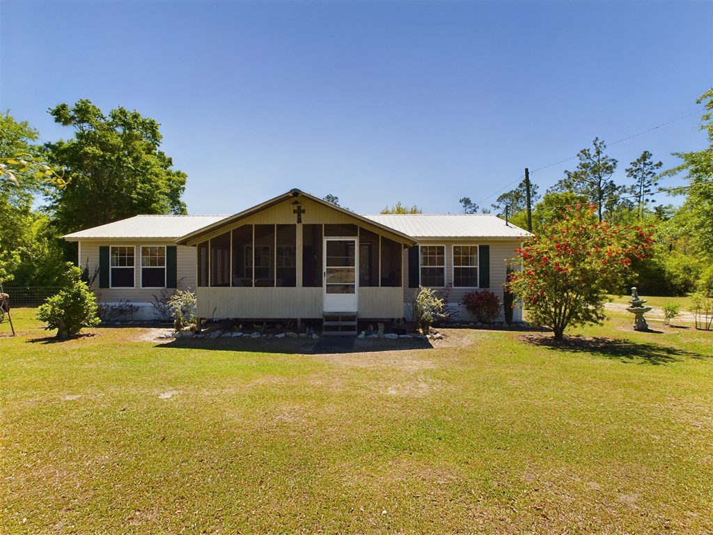 Single-story home with a covered front porch, light metal roof, and broad lawn.