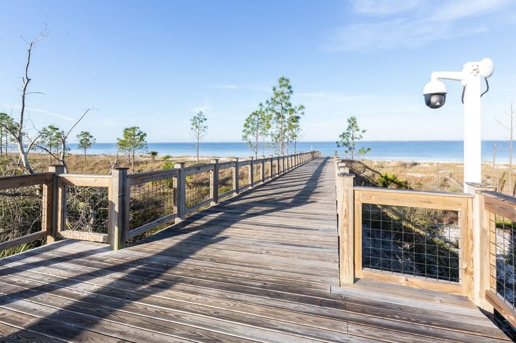 Wooden boardwalk crosses coastal dunes to a sandy beach and ocean.