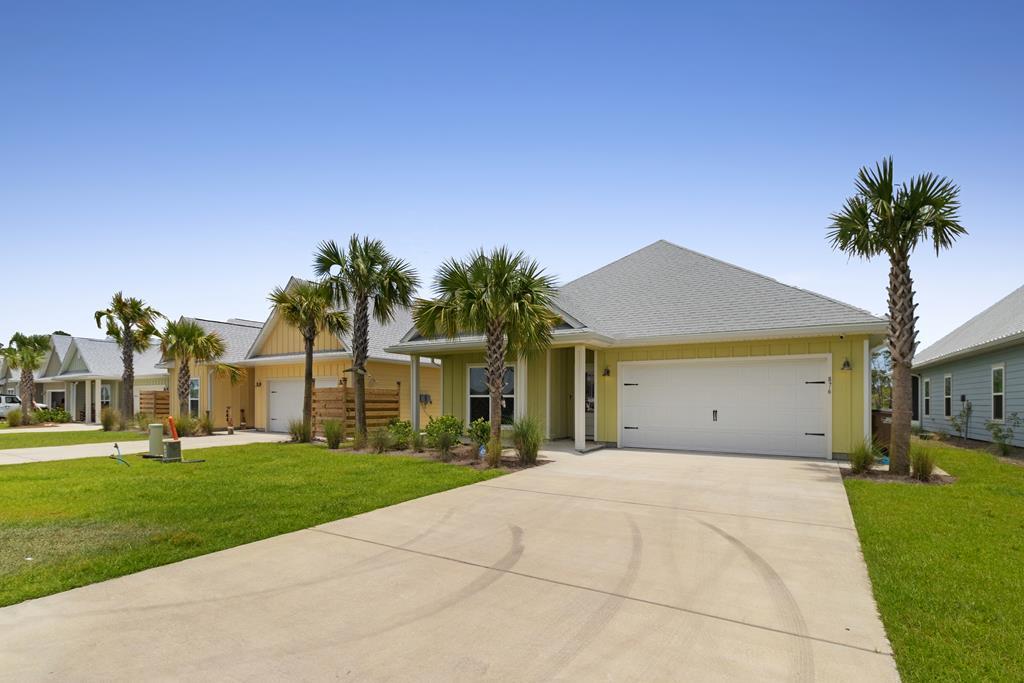 Yellow single-story home with a double garage, wide driveway, and palm trees.