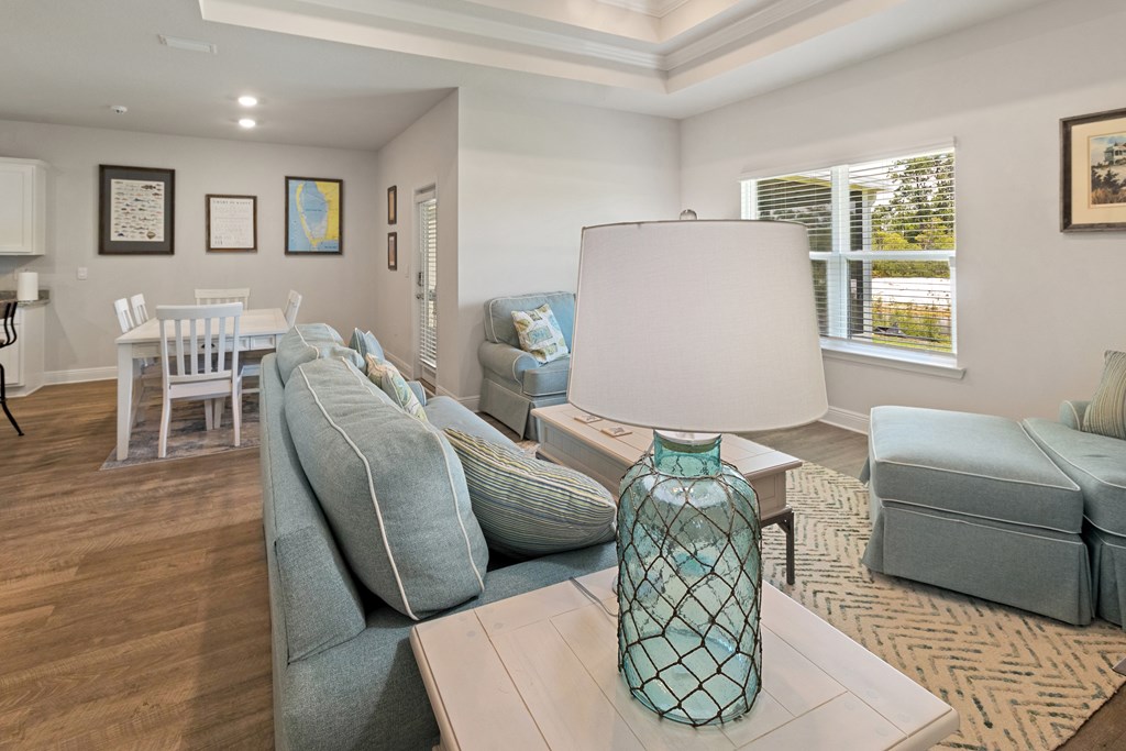 Living room with pale blue seating, patterned rug, and dining area.