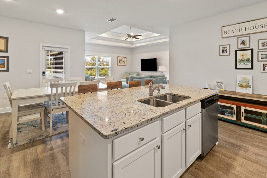 Open kitchen with granite island and sink, dining table, and living room beyond.