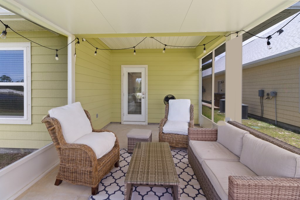 Covered patio with wicker seating, a patterned rug, and string lights.