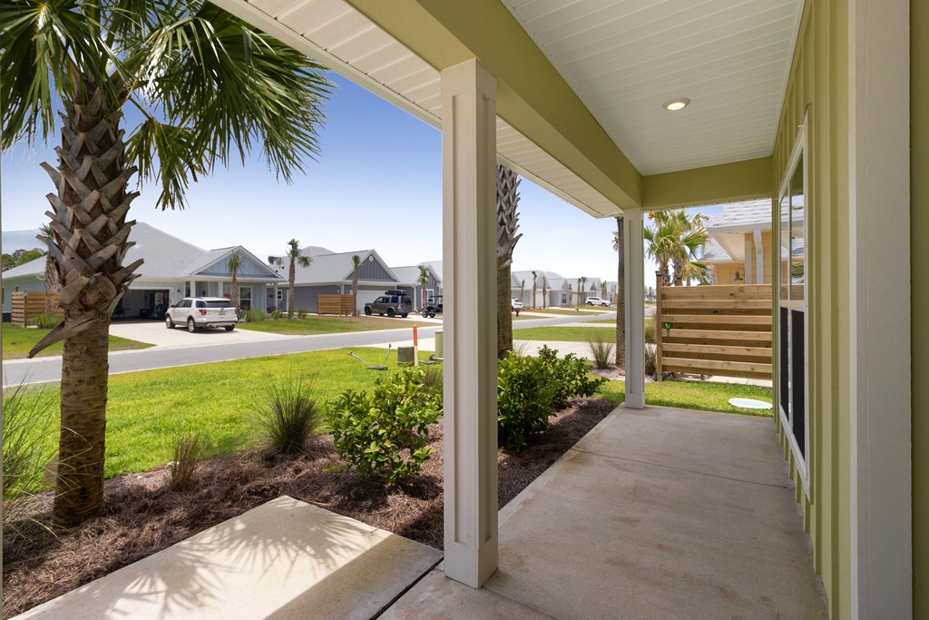 Covered front porch overlooking a palm-lined yard and neighboring homes across the street.