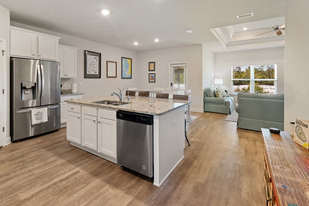 Open-plan kitchen with a granite island, stainless steel appliances, and living area beyond.