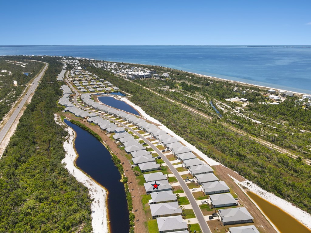 Aerial view of homes beside a canal near the Gulf shoreline, with 876 Backwater Rd marked.