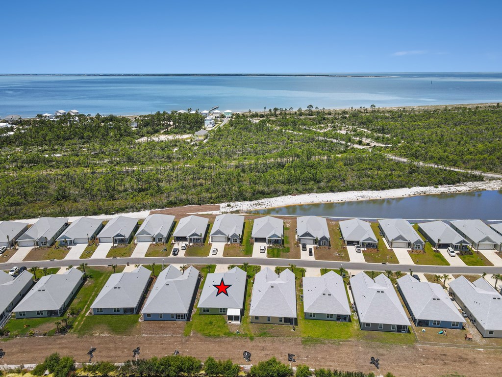 Aerial view of the star-marked home, with a waterway, shoreline, and coastal waters beyond.