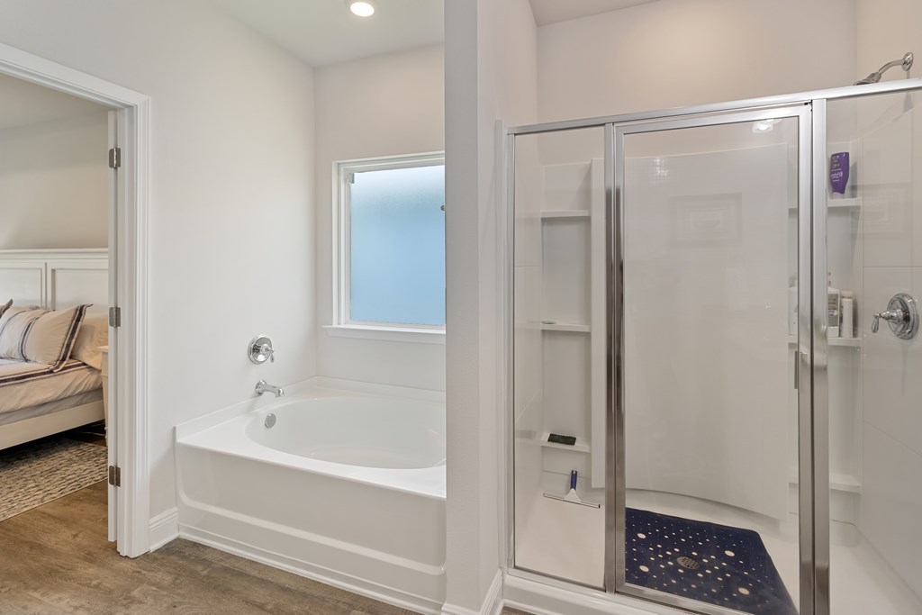 Bathroom with a white soaking tub beneath a frosted window and a glass-enclosed shower.