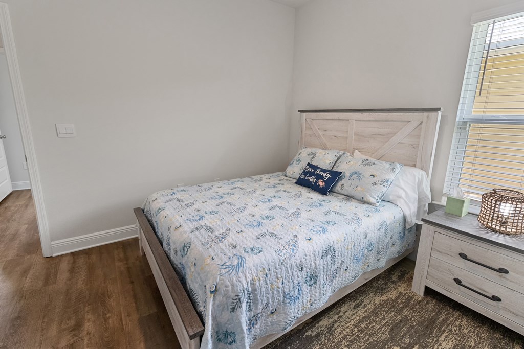 Bedroom with a light wood bed, blue-and-white patterned bedding, and a matching bedside dresser.
