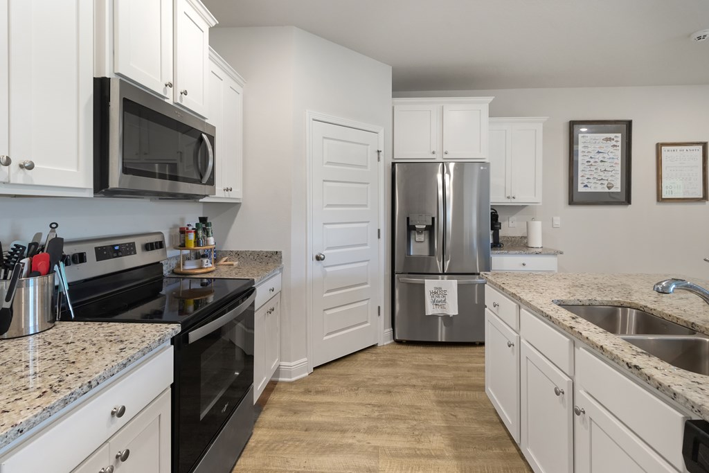 Kitchen with white cabinets, granite counters, stainless appliances, and a double-basin sink.