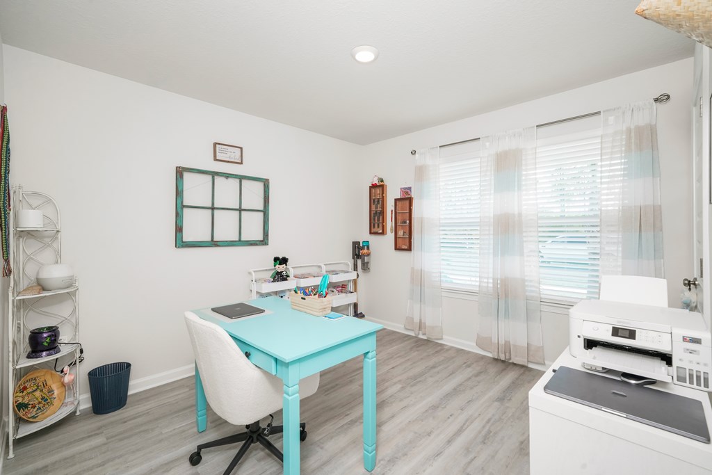 Bright home office with a turquoise desk, printer, and large curtained windows.