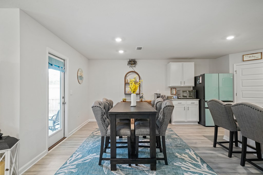 Dining area with a dark table, gray chairs, blue rug, and mint-green refrigerator.