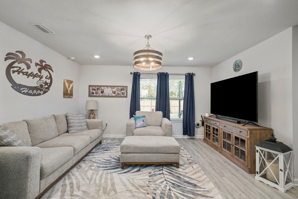 Living room with a gray sectional, patterned rug, and television on a wooden console.