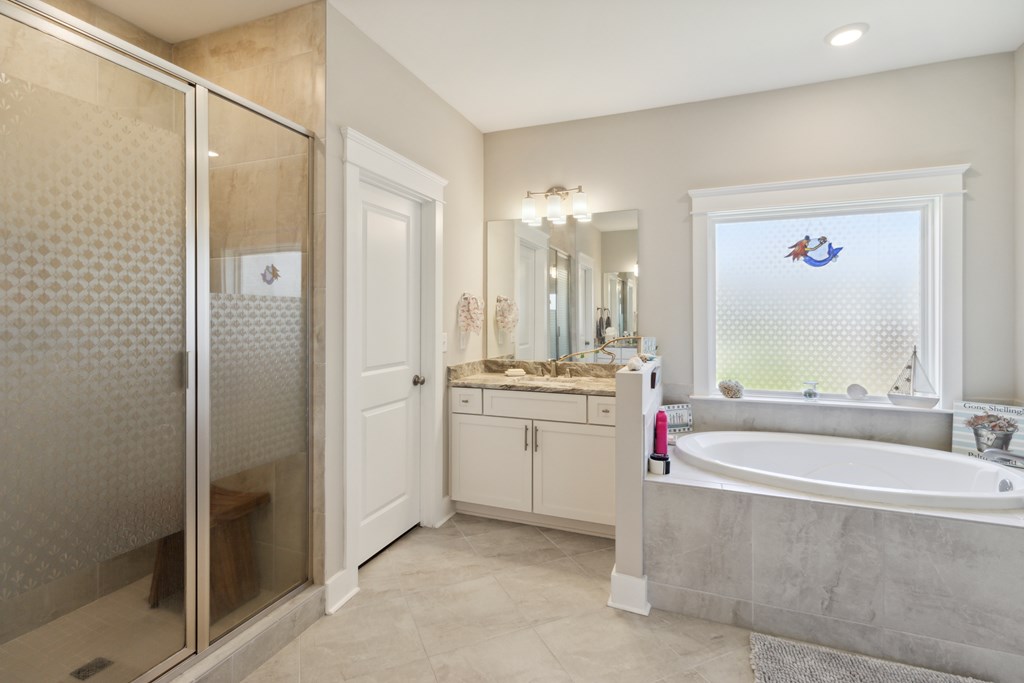 Bathroom with a glass shower and oval soaking tub beneath a window.