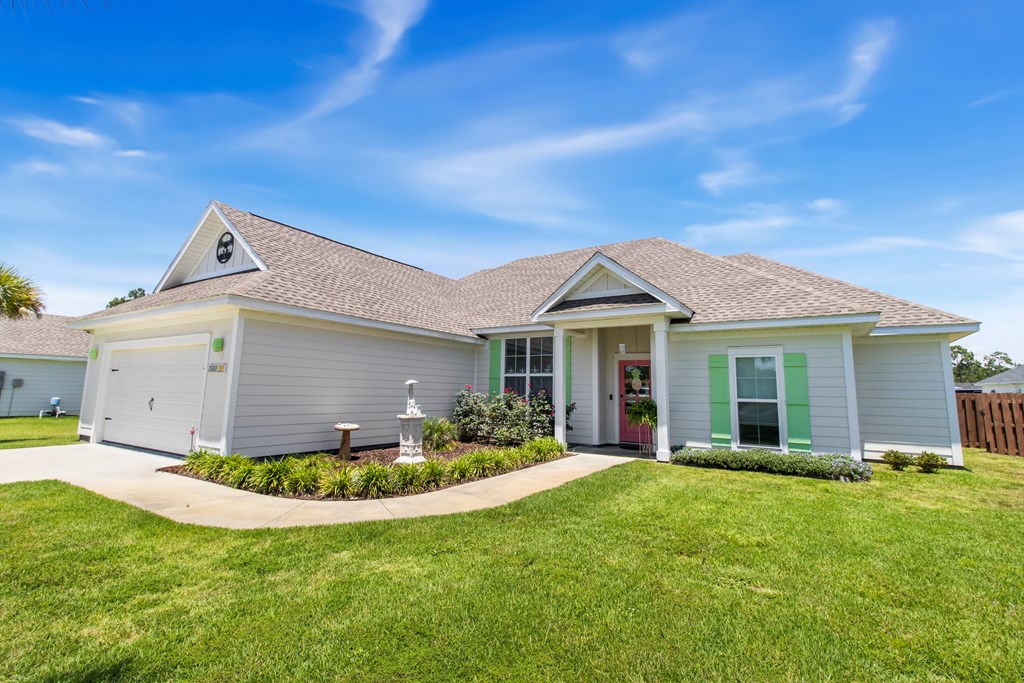 Gray single-story home with an attached garage, green shutters, and a curved walkway across the front lawn.