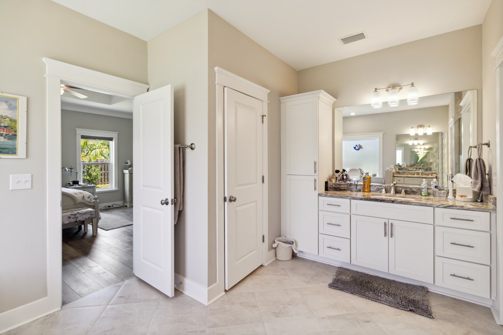 Bathroom with a long double-sink vanity and an open doorway to a bedroom.