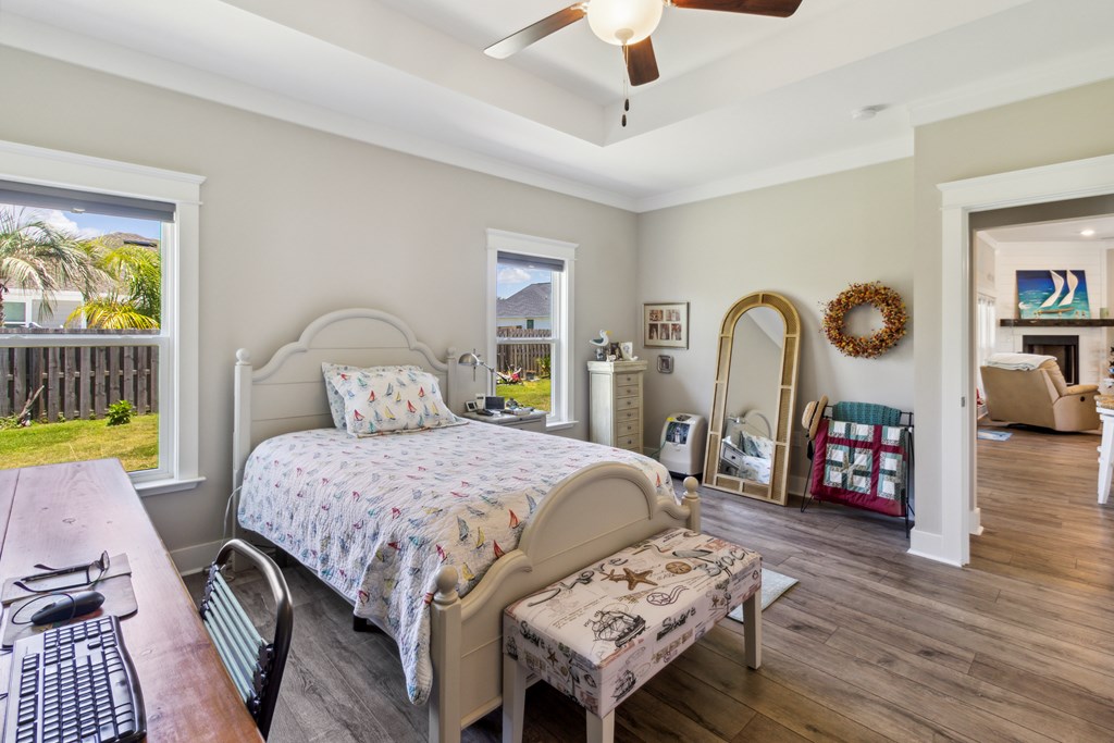 Furnished bedroom with sailboat-patterned bedding, two windows, and a tray ceiling.