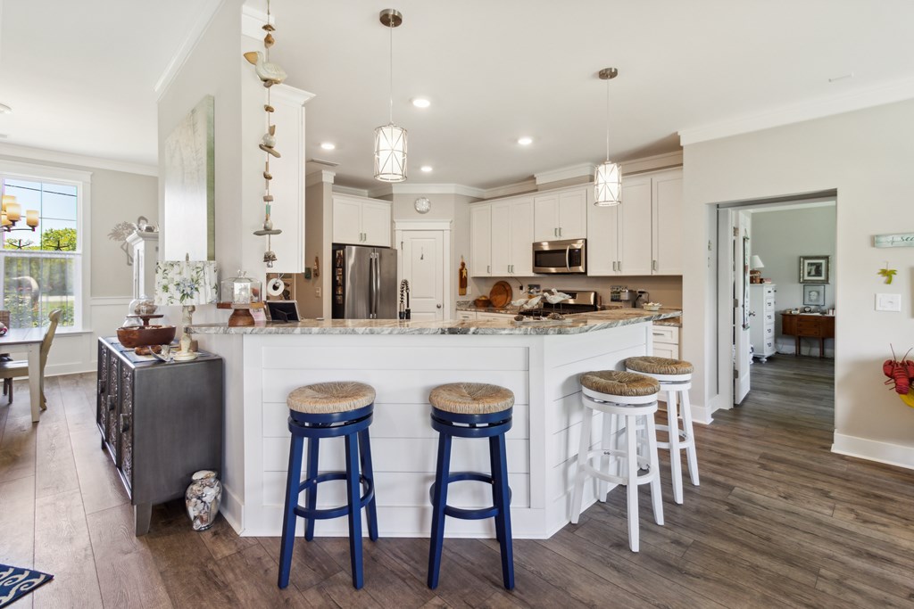 Kitchen with a large white island, marble-look countertop, and blue and white stools.