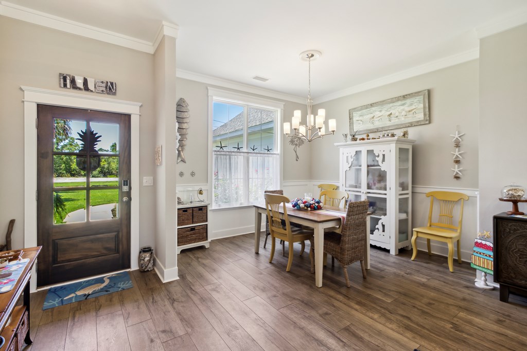 Dining room with a wood table, white display cabinet, large window, and glass-paneled entry door.
