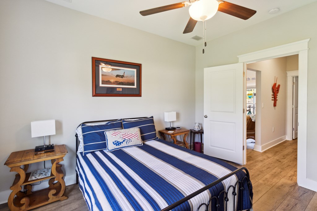 Furnished bedroom with a blue-and-white striped bed, wooden bedside tables, and an open doorway.