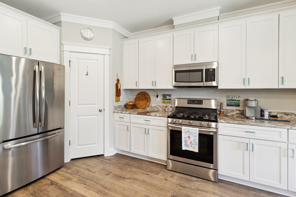 Kitchen with white cabinets, stainless steel appliances, and wood-look flooring.