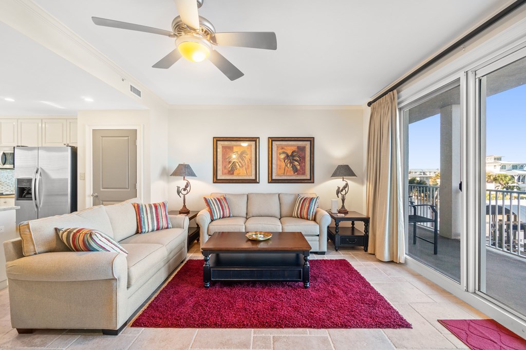 Condo living room with cream sofas, a magenta rug, and sliding doors to a balcony.