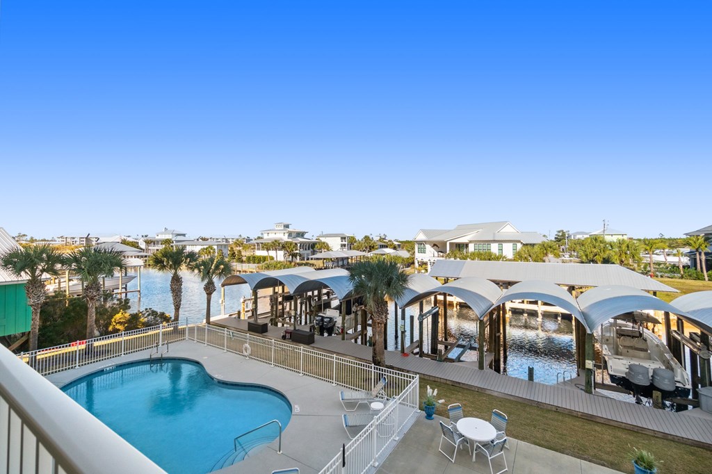 Condominium pool overlooks a marina with covered boat slips and palm trees.