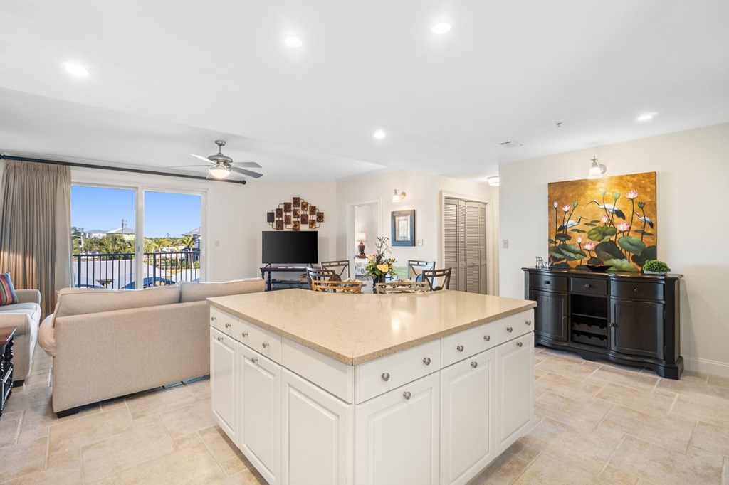 Open-plan kitchen with a large white island, adjoining living and dining areas, and sliding doors to a balcony.