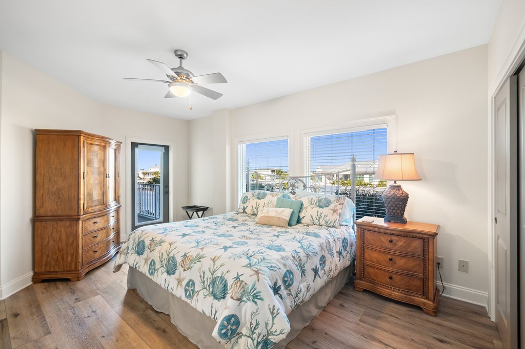 Furnished bedroom with floral bedding, wooden dressers, and a glass door to the balcony.