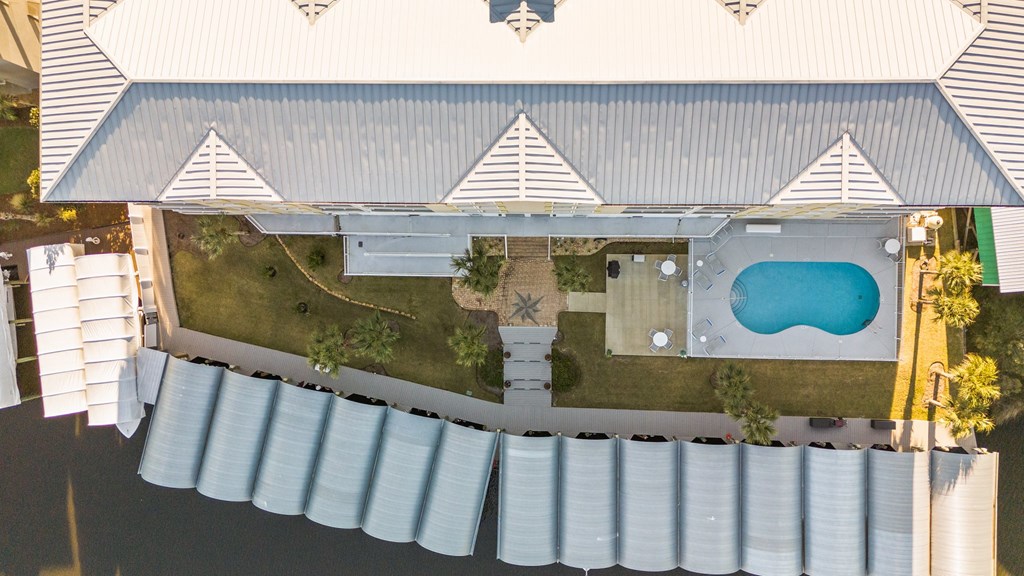 Aerial view of a condominium courtyard with a swimming pool and covered waterfront boat slips.