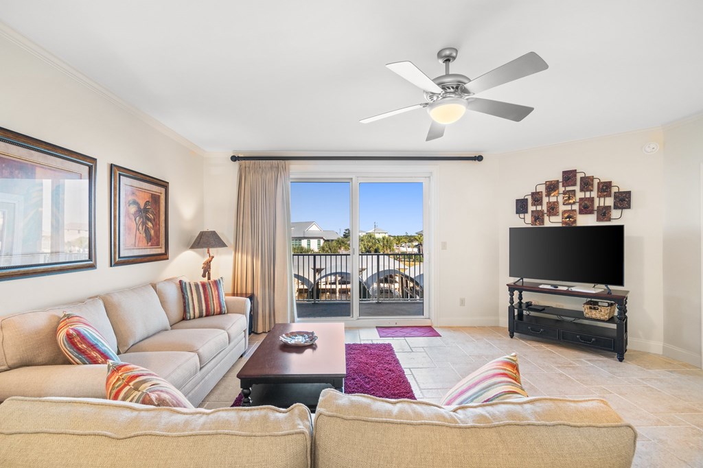 Furnished living room with tiled floors, sectional sofas, and sliding doors to a balcony.