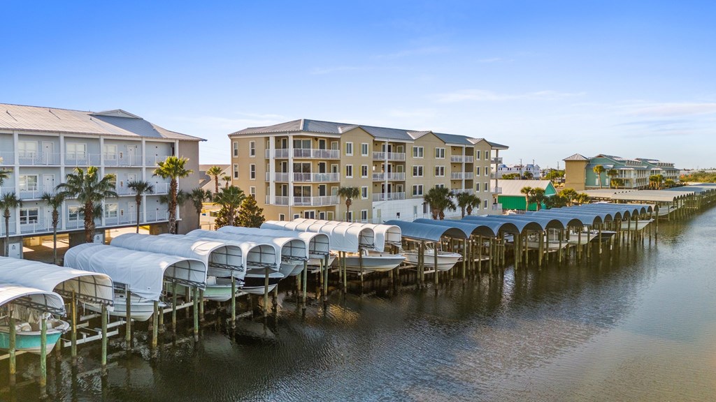 Waterfront condominium buildings and a marina with rows of covered boat slips.