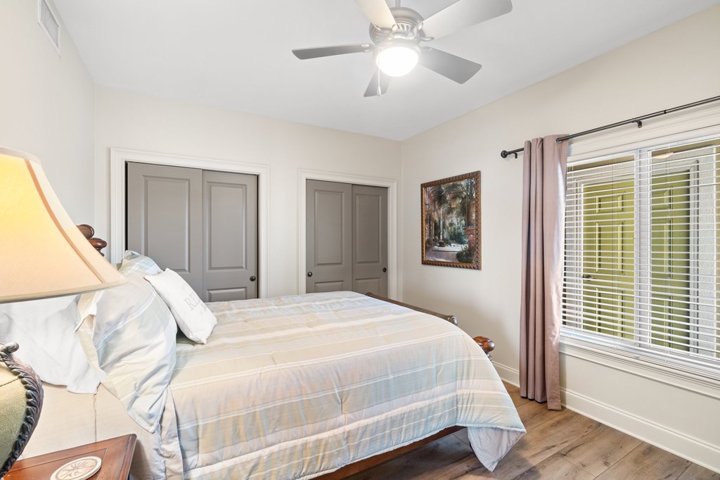 Bedroom with pale striped bedding, gray doors, and a window with mauve curtains.