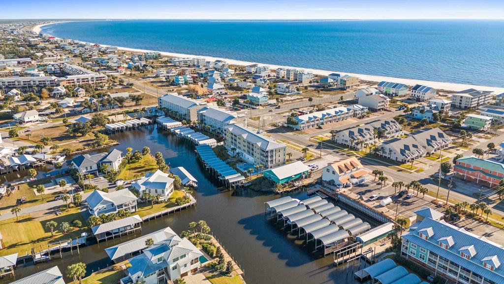 Aerial view of Mexico Beach homes and condos beside a canal flowing toward the Gulf shoreline.
