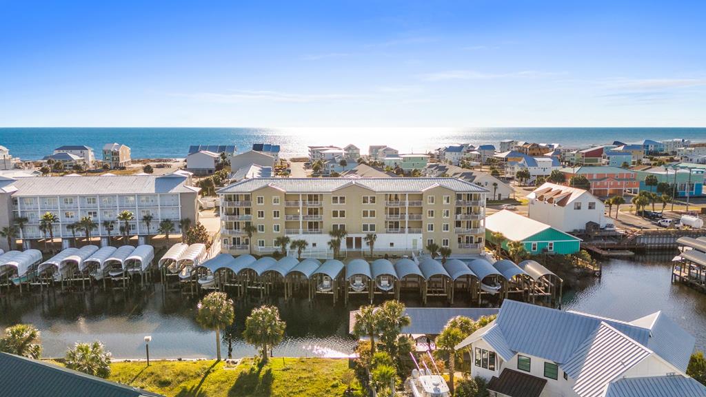 Coastal condominium buildings and covered boat slips between a canal and the Gulf of Mexico.