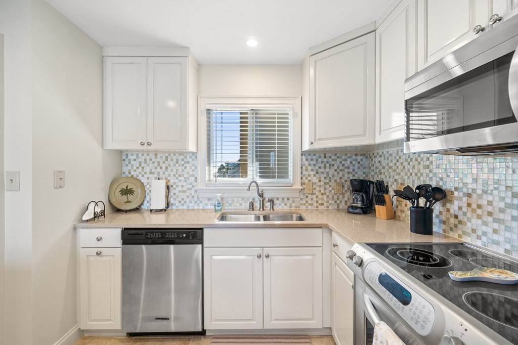 Kitchen with white cabinets, mosaic tile backsplash, and stainless-steel appliances.