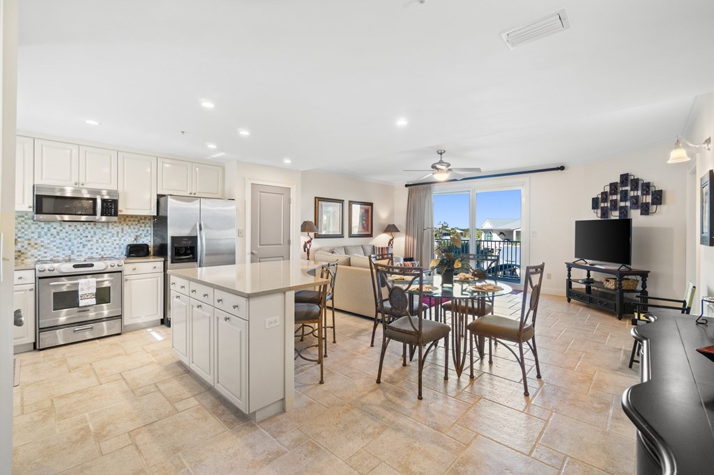 Open condo kitchen and dining area with a balcony overlooking the water.