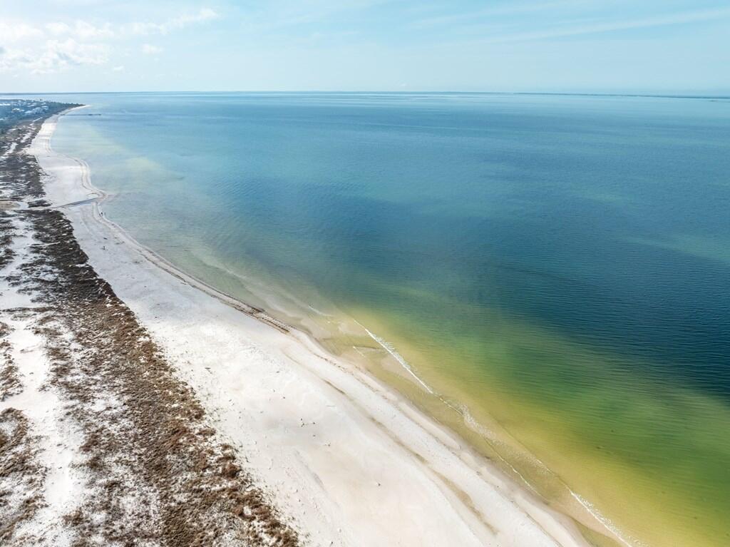 Aerial view of a sandy coast beside blue-green water.